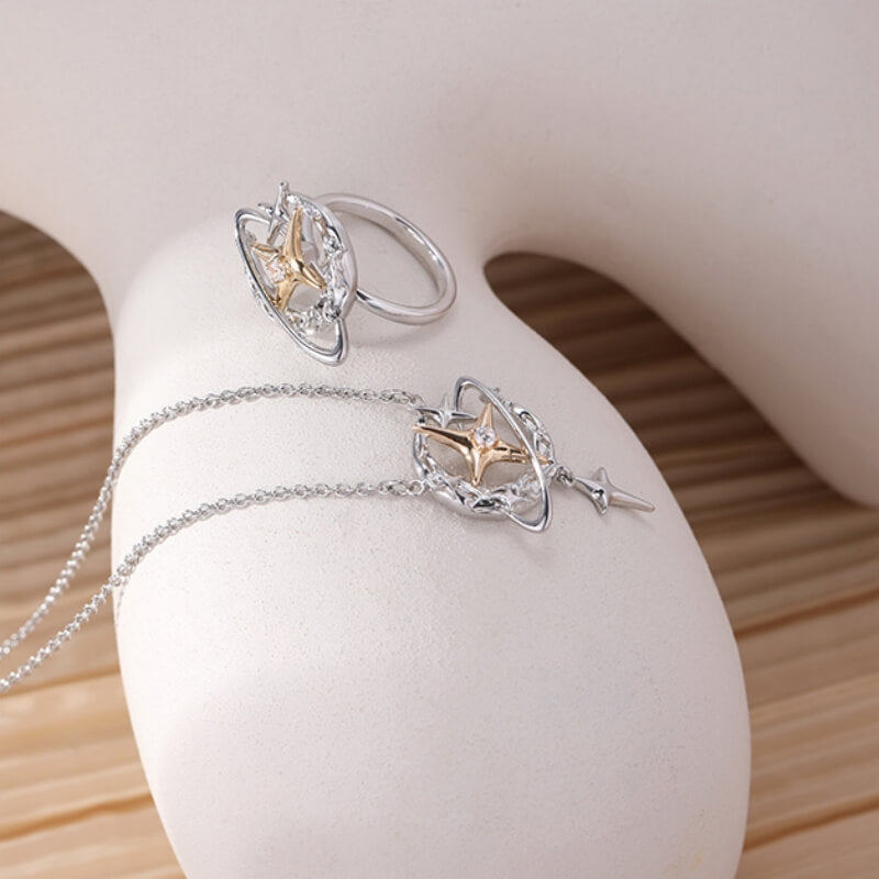 Silver-tone planet-and-star pendant necklace and matching ring with gold-tone star centres displayed on a white stand.