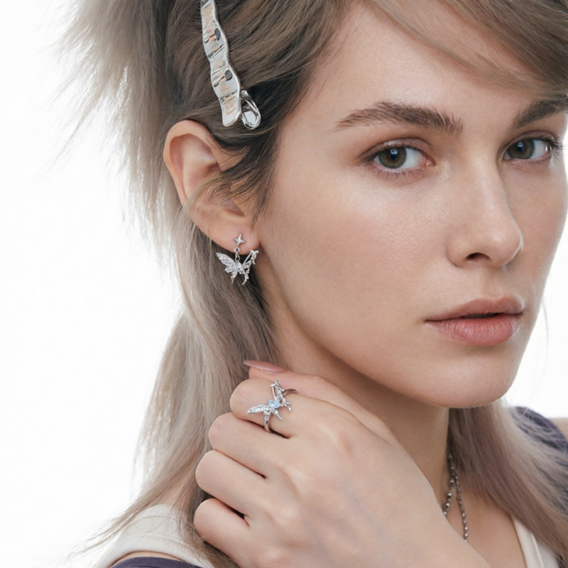 Model wearing a silver-tone butterfly earring and matching butterfly ring with pale blue accents.