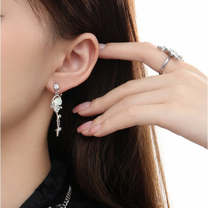 Close-up of a silver-tone half-butterfly-wing drop earring with a pale iridescent detail and dangling star, worn by a model.