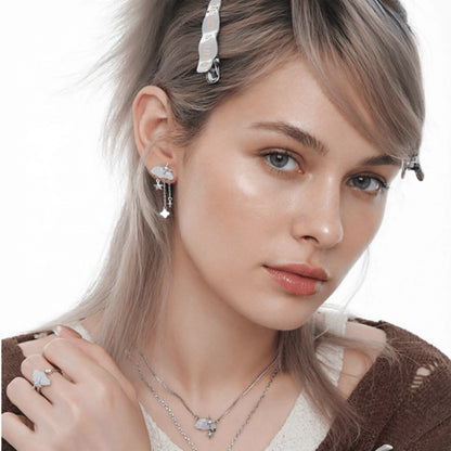 Model wearing white cloud and dangling star earrings, a matching ring and layered necklaces.