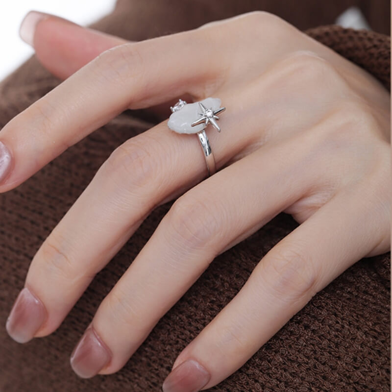 Close-up of a silver-tone ring with a white cloud and small star detail, worn on a hand.
