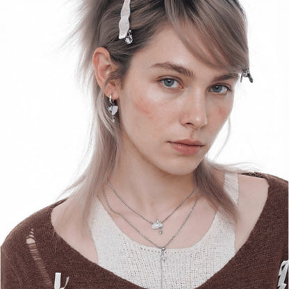 Model wearing layered silver-tone necklaces with white cloud and star details and matching earrings.