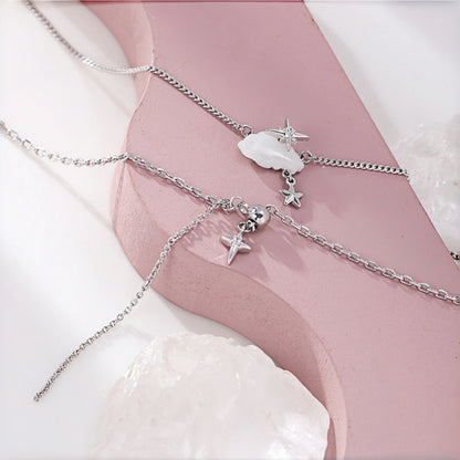 Cloud and star layered necklace close-up, three delicate silver chains with a mother-of-pearl cloud charm, star charm and small bell charm