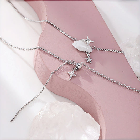 Cloud and star layered necklace close-up, three delicate silver chains with a mother-of-pearl cloud charm, star charm and small bell charm