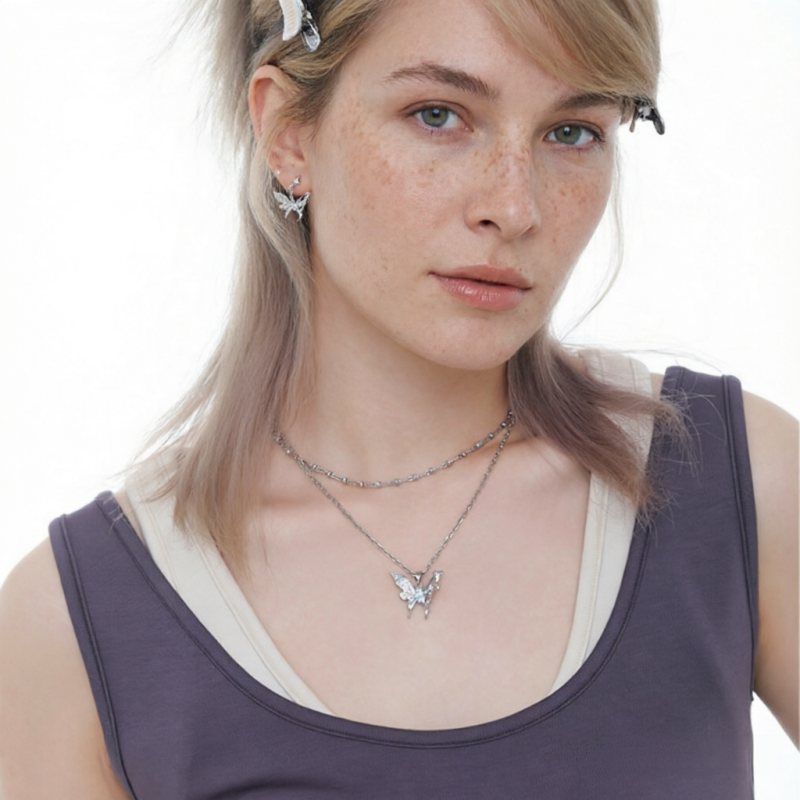 Model wearing a silver-tone butterfly pendant necklace and matching butterfly earrings.