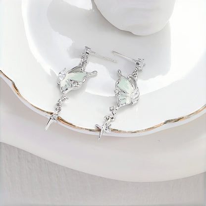 Fairy iridescent butterfly drop earrings close-up, pair of silver butterfly charms with mint enamel wings and clear crystal accents, on a white plate