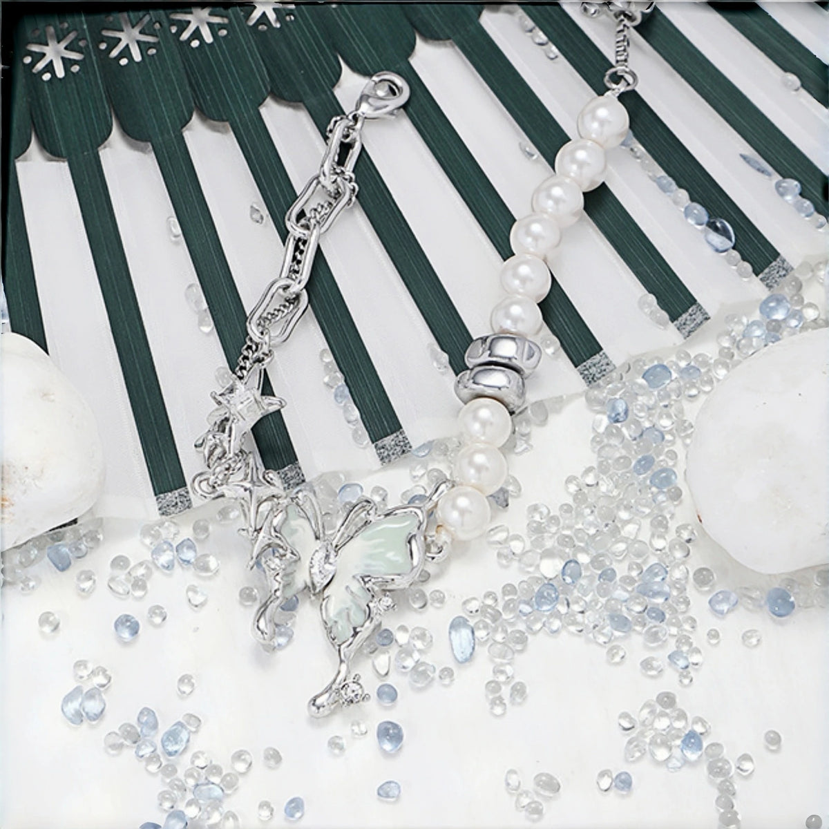 Fairy iridescent butterfly bracelet close-up, layered silver chain and pearl beaded bracelet with star and mint enamel butterfly charms, scattered with clear and blue crystal beads