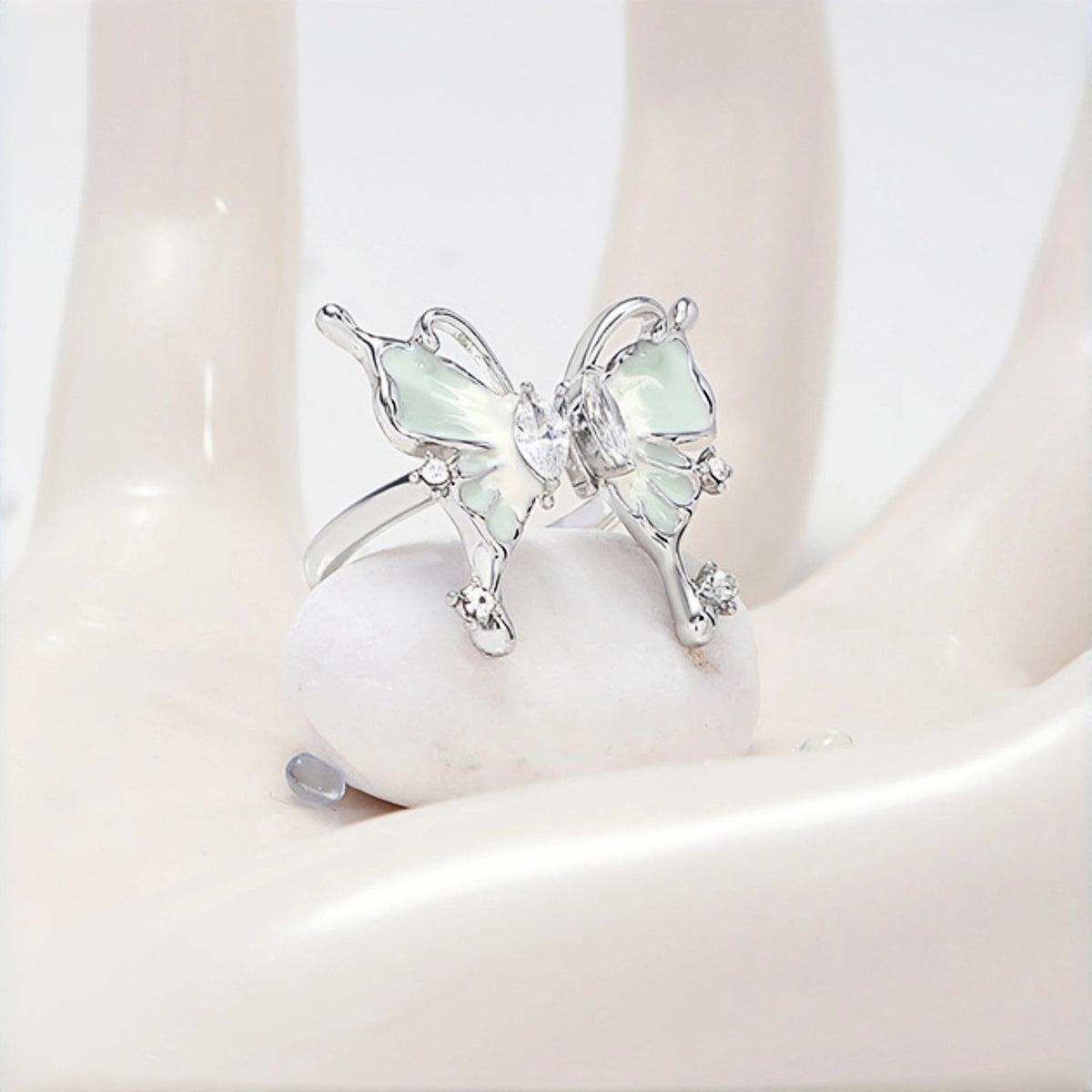Fairy iridescent butterfly ring close-up, open silver ring with a mint enamel butterfly charm and clear crystal accents