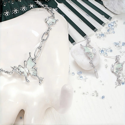 Fairy iridescent butterfly necklace displayed on a bust, silver paperclip chain necklace with a mint enamel butterfly charm and star accents, shown beside a pair of matching drop earrings, scattered with crystal beads