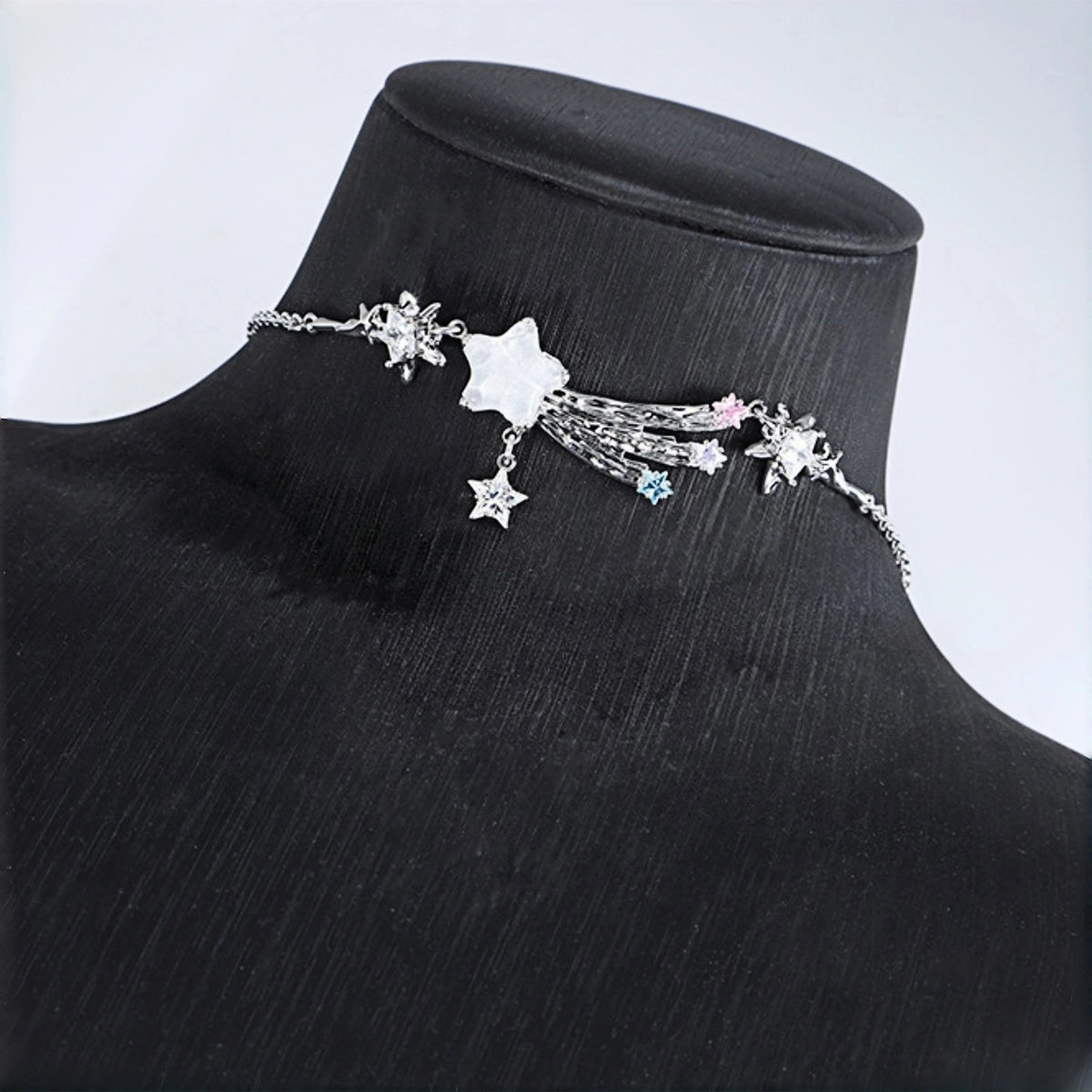 Fairy shooting star necklace on display bust, layered silver chains with a large mother-of-pearl star and tasselled strands with pastel crystal star charms