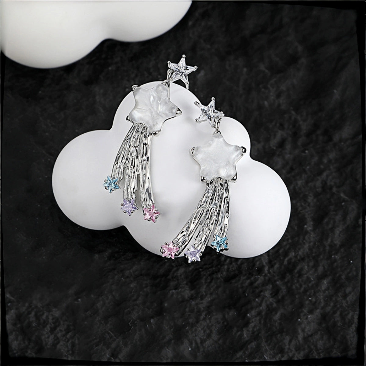 Fairy shooting star drop earrings close-up, pair of silver star studs with mother-of-pearl star charms, tasselled strands and pastel crystal star drops