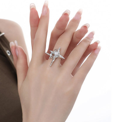 Close-up of a sculptural silver-tone four-point star ring worn on a model's hand.