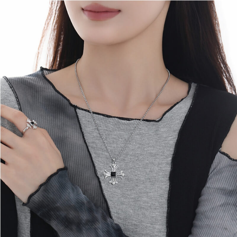 Front view of a model wearing a silver-tone cross pendant necklace and matching cross ring with black accents.