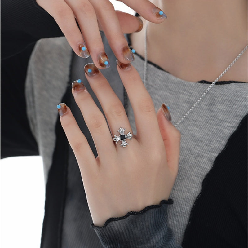 Model wearing a silver-tone gothic cross ring with a black square centre.