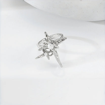 Grunge star cross ring close-up, open silver band with an asymmetric four-point star and cross charm featuring a pearl accent