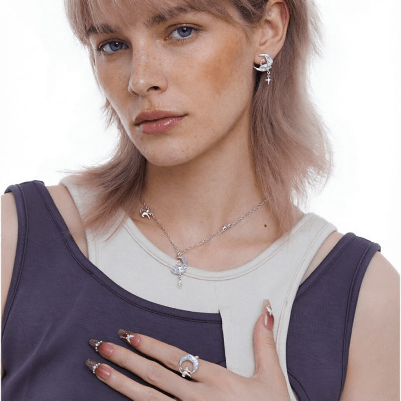 Model wearing a silver-tone crescent moon earring, matching cat-and-moon necklace and ring with small star details.