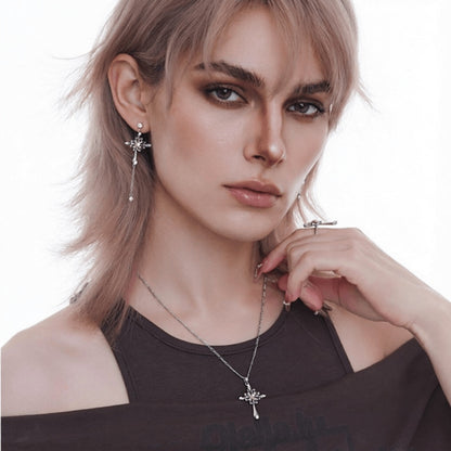 Model wearing a silver-tone ornate cross necklace and a long drop earring with a matching cross design.