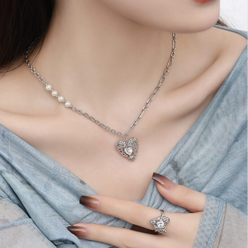 Model wearing a silver-tone openwork heart pendant necklace and matching ring with clear central stones.