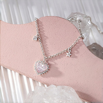 Pink heart princess bracelet close-up, pink crystal heart charm with clear crystal halo on a chain with dangling clear heart and star charms, on a pink display stand