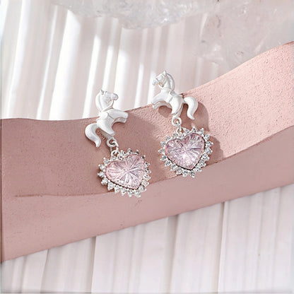 Pink heart princess earrings close-up, pair of pink crystal heart drops with clear crystal halos, topped with white enamel unicorn studs
