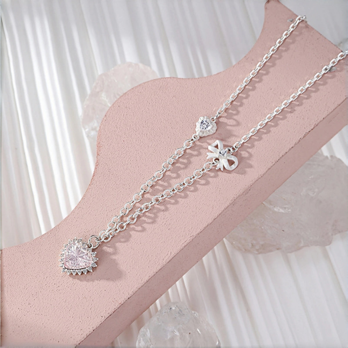 Clear crystal heart pendant necklace close-up, layered silver chains with a clear crystal heart pendant, small flower charm and bow charm