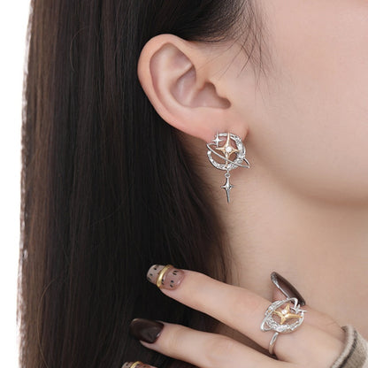 Close-up of a silver-tone planet earring with a dangling star charm, worn with a matching ring.