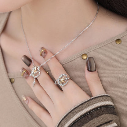 Model wearing a silver-tone planet pendant necklace and matching ring with gold-tone star details.