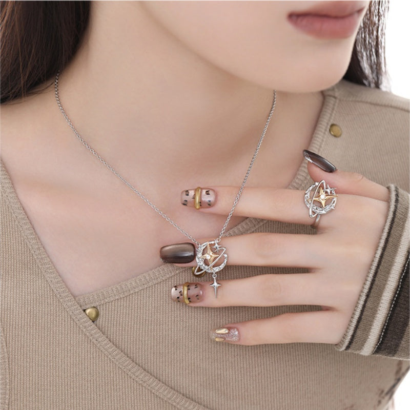 Model wearing a silver-tone planet pendant necklace with a dangling star and a matching orbital ring with gold-tone star centres.