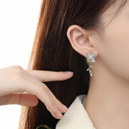 Side view of a silver-tone rose drop earring with small leaves and a dangling stem.