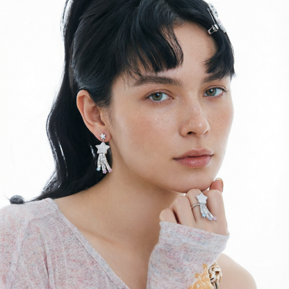 Model wearing a white star drop earring with trailing details and a matching star ring.
