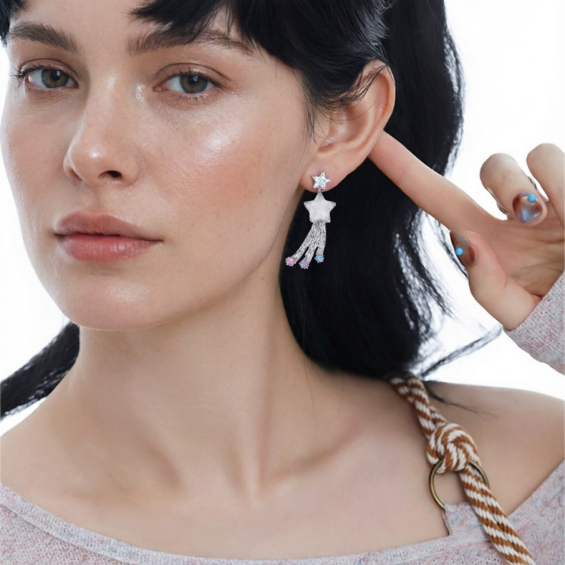 Close-up of a white star drop earring with three trailing silver-tone strands, worn by a model.