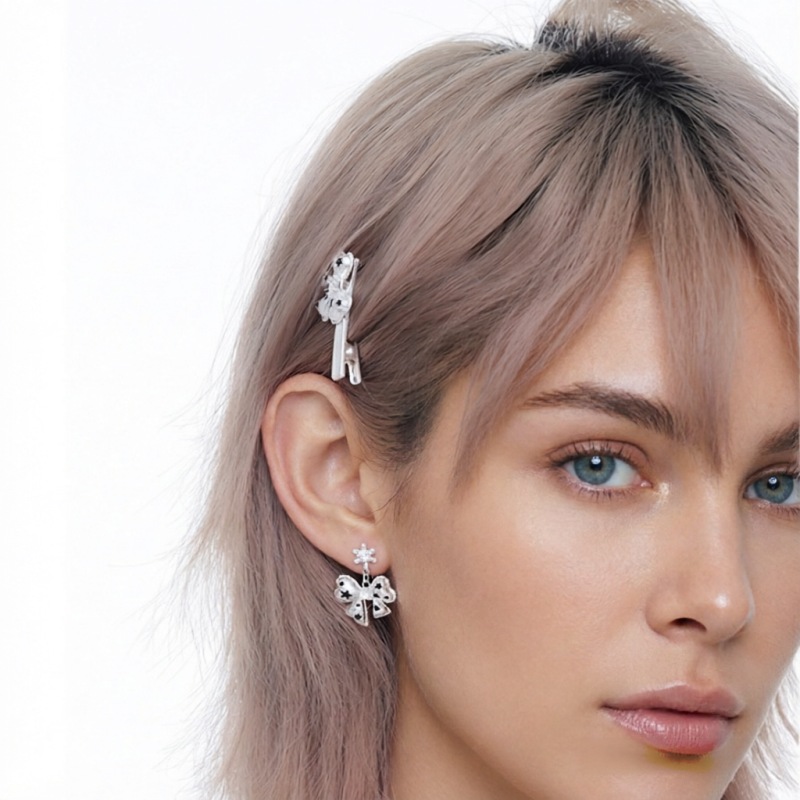 Close-up of a model wearing a white bow drop earring with black star details and a matching bow hair clip.