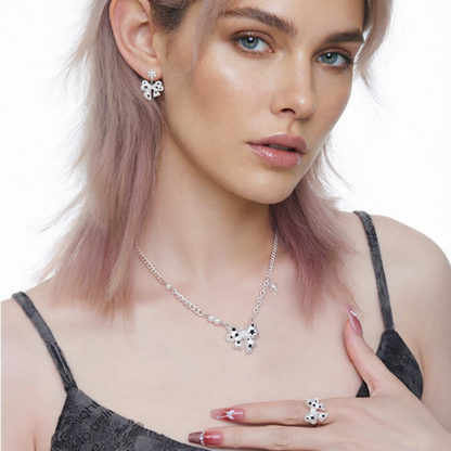 Model wearing a white bow necklace, matching earrings and ring with black star details.