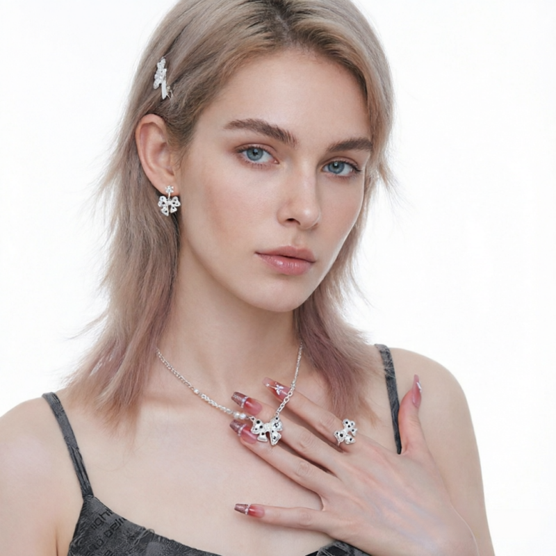 Model wearing white bow earrings, a matching bow necklace and ring with black star details.