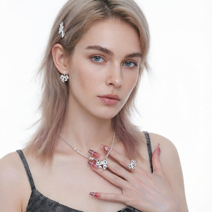 Model wearing white bow earrings, a matching bow necklace and ring with black star details.