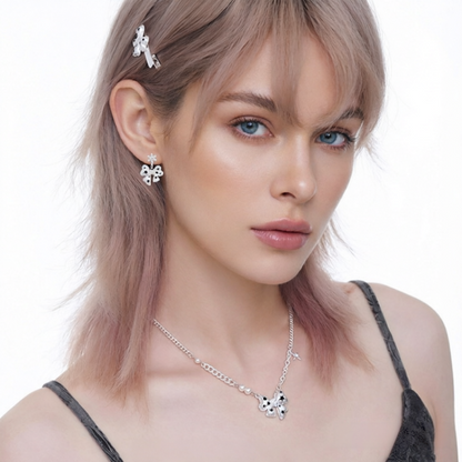 Model wearing a white bow pendant necklace and matching bow earrings with black star details.