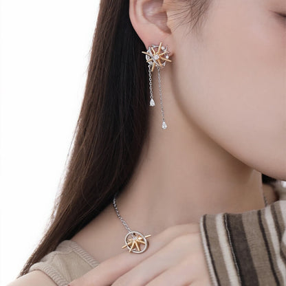 Close-up of a two-tone starburst earring with two dangling chains, worn with a matching pendant necklace.