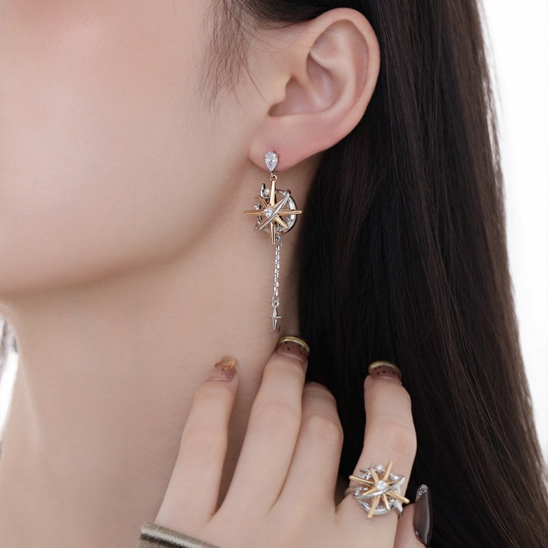 Close-up of a two-tone starburst drop earring with a long chain and a matching starburst ring.