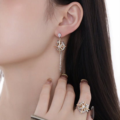 Close-up of a two-tone starburst drop earring with a long chain and a matching starburst ring.
