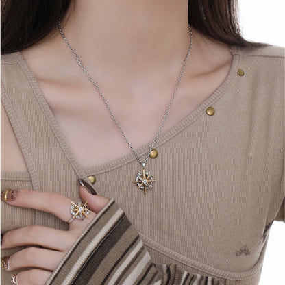Model wearing a two-tone starburst pendant inside a circular frame with a matching statement ring.