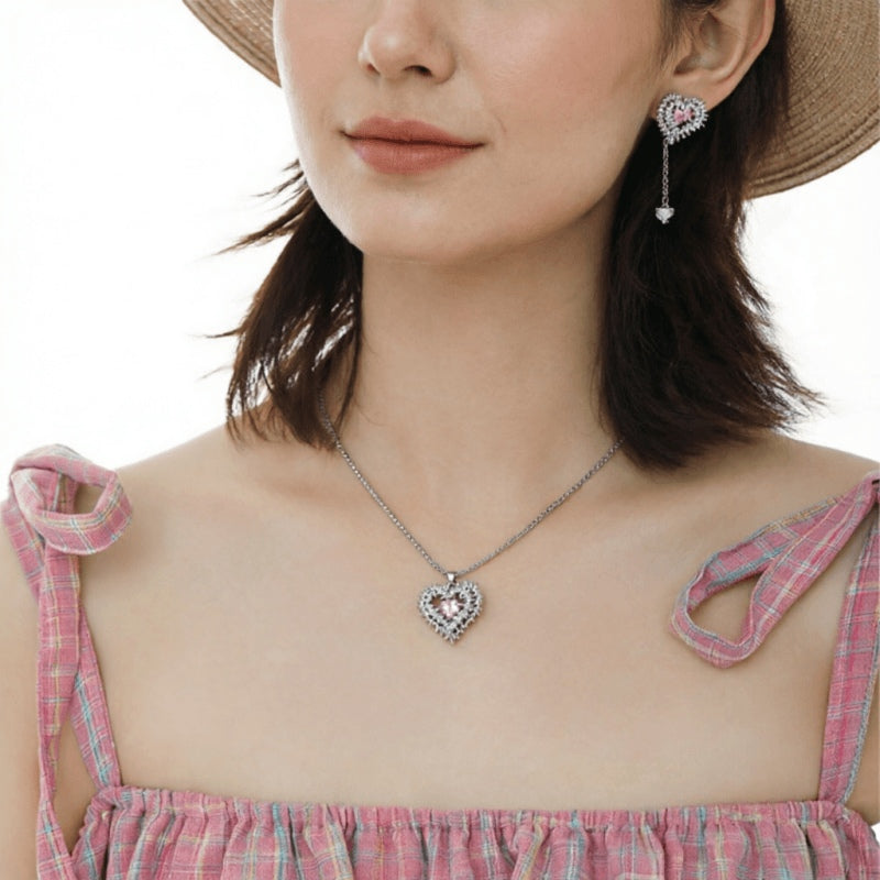Model wearing a silver-tone thorn-framed heart necklace and matching long drop earring.