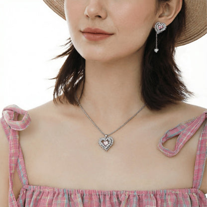 Model wearing a silver-tone thorn-framed heart necklace and matching long drop earring.