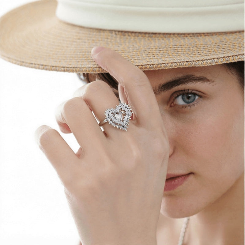 Model in a straw hat wearing a silver-tone thorn-framed heart ring with a pale pink centre.