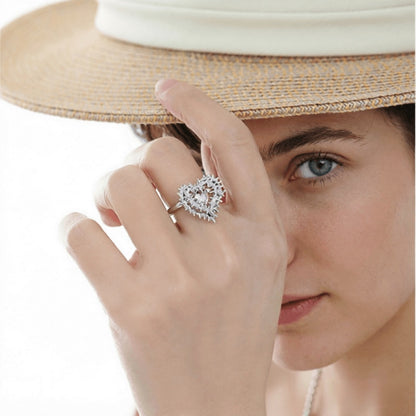 Model in a straw hat wearing a silver-tone thorn-framed heart ring with a pale pink centre.
