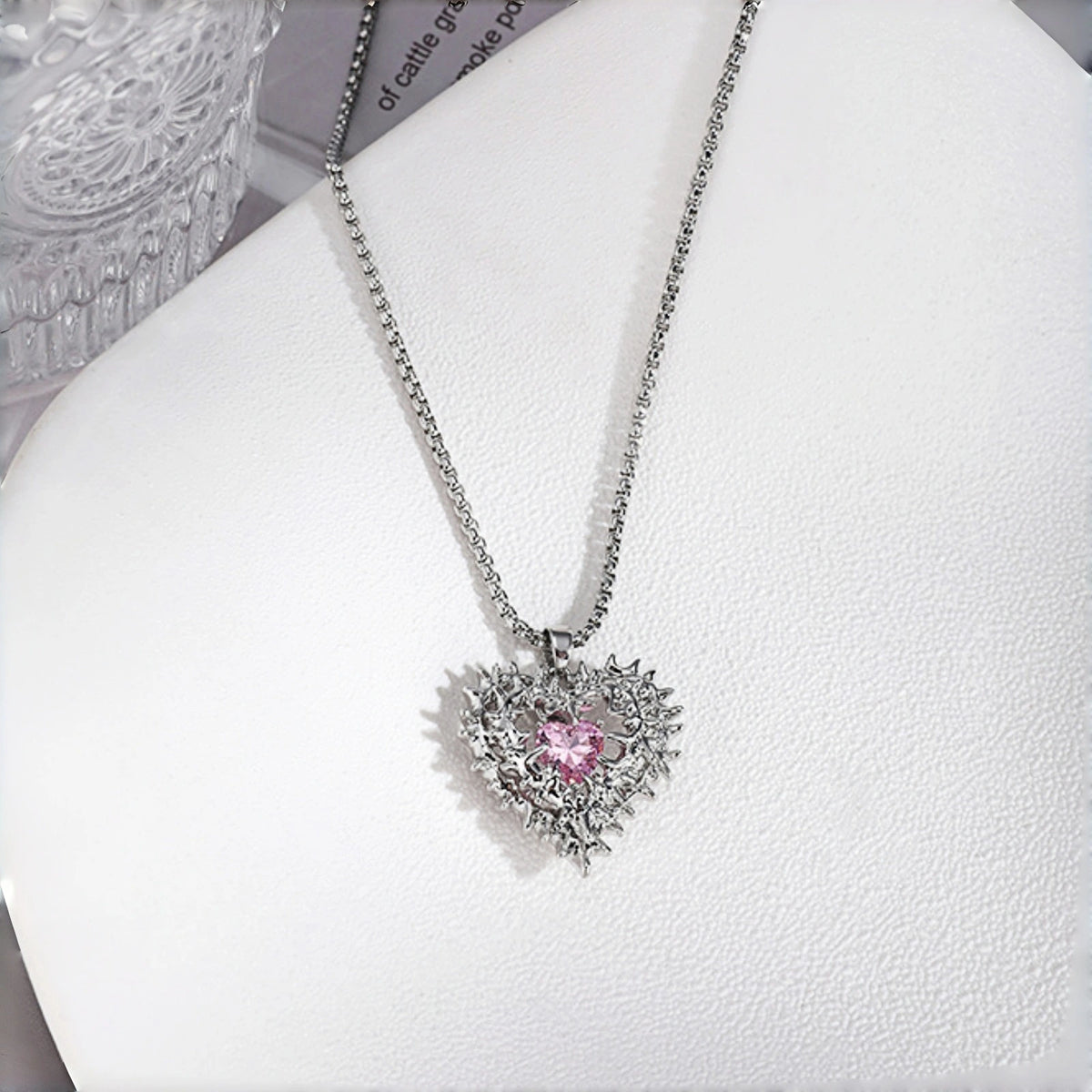 Thorned pink heart pendant necklace close-up, silver thorn-framed heart pendant with pink crystal centre stone on a box chain