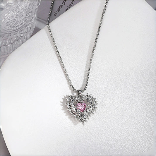 Thorned pink heart pendant necklace close-up, silver thorn-framed heart pendant with pink crystal centre stone on a box chain