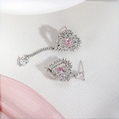 Thorned pink heart earrings close-up, pair of silver thorn-framed heart earrings with pink crystal stones and a mismatched dangling charm