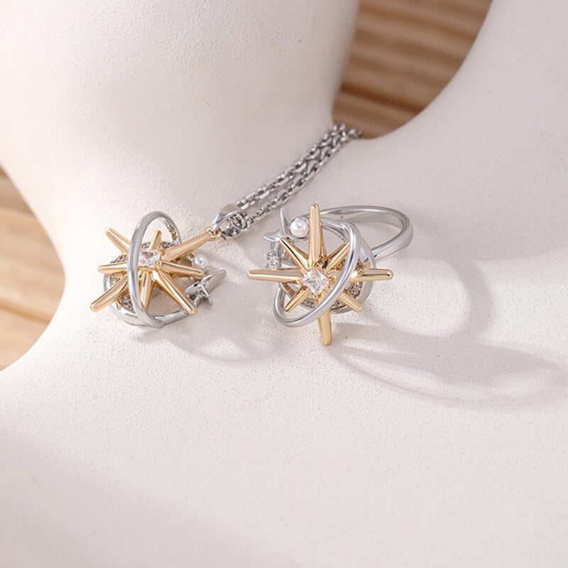 Close-up of a matching starburst pendant and ring with gold-tone rays and silver-tone orbital frames.