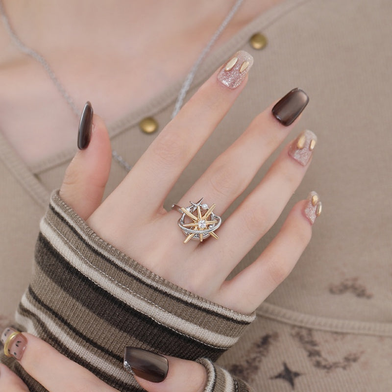 Model wearing a two-tone ring with a gold-tone starburst inside a silver-tone orbital frame.
