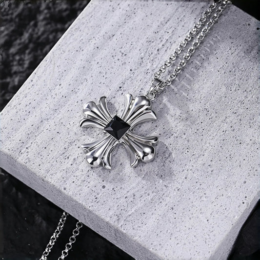 Gothic cross necklace close-up, silver cross pendant with black square stone on a grey stone surface